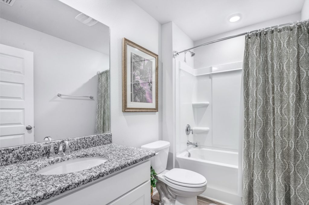 Bright and clean modern bathroom with granite countertop and elegant decor.