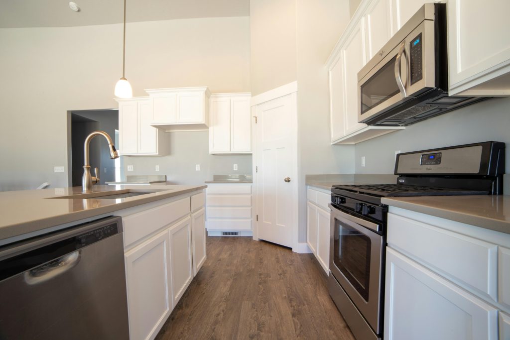Spacious modern kitchen with white cabinets and stainless steel appliances.