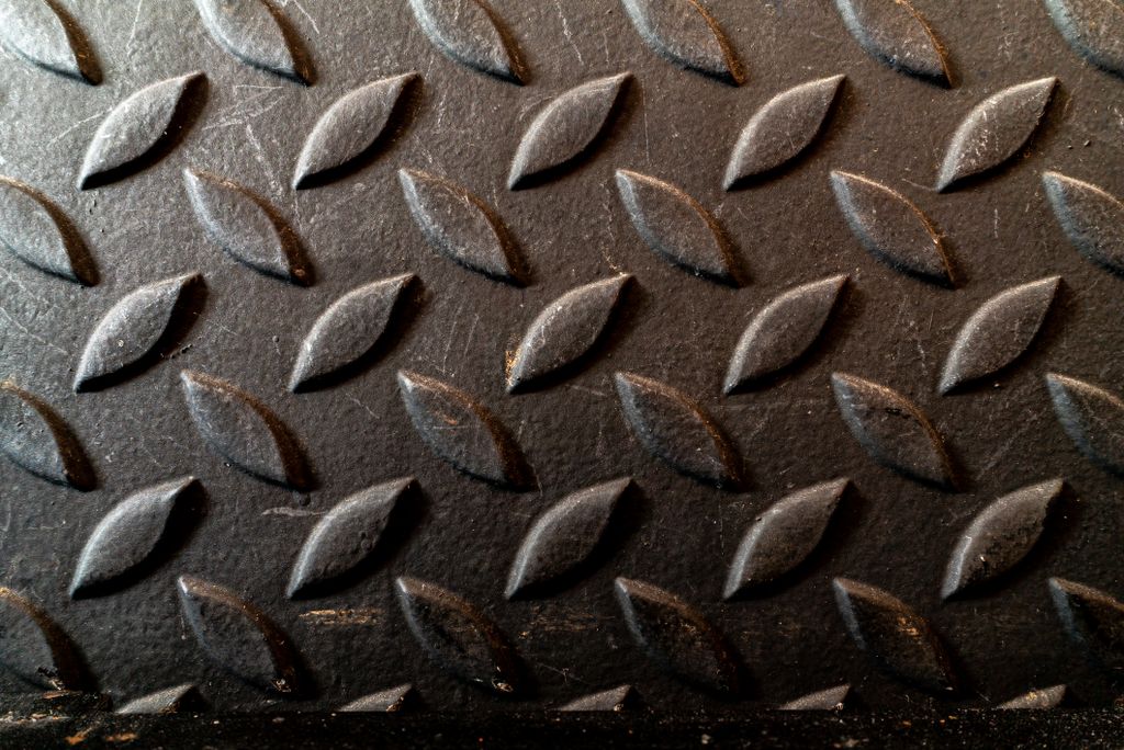 Close-up of a diamond plate metal surface with an oblique textured pattern.