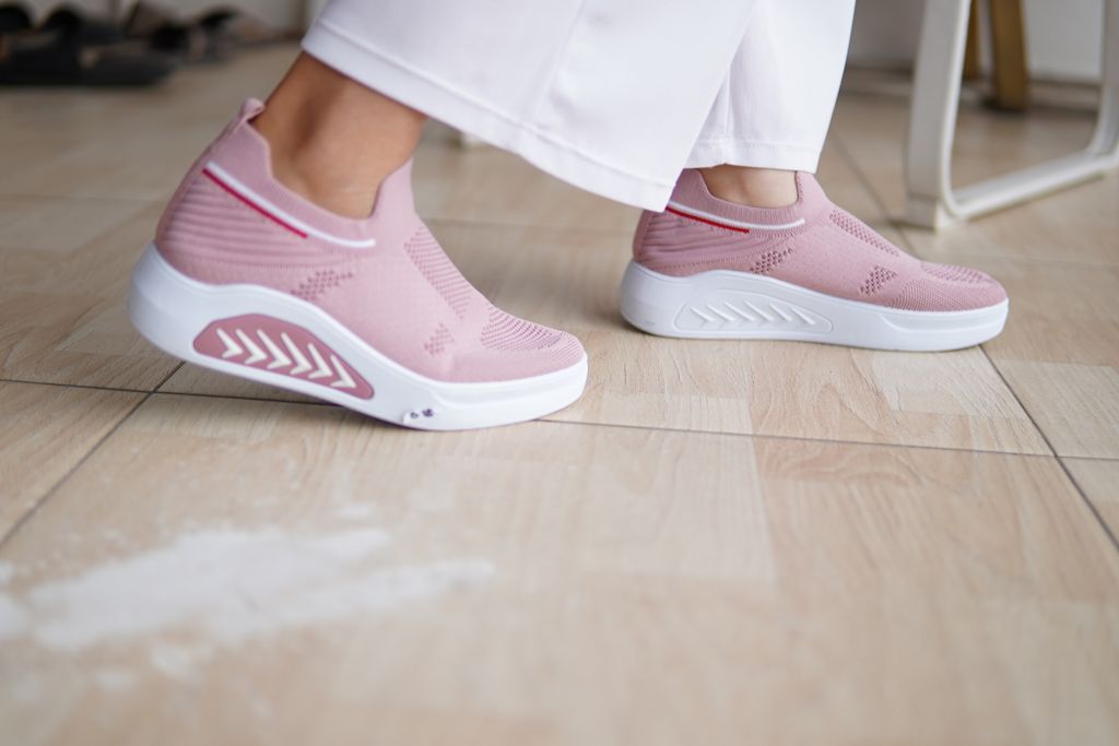 Close-up of fashion-forward pink sneakers worn indoors on a wooden floor.